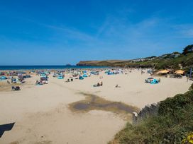 A beach with people and umbrellas at 9 Tides Reach in Wadebridge