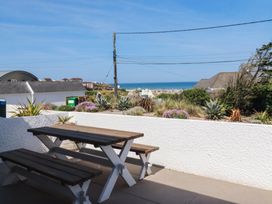 An outdoor seating area with a table and bench overlooking the sea at 9 Tides Reach in Wadebridge