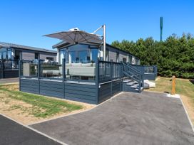 A deck with a couch and umbrella at Lakewood Plot 3 St. Osyth