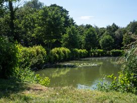 A pond with water lilies and surrounding trees at Lakewood Plot 3 St. Osyth