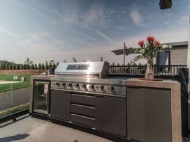 An outdoor kitchen with a grill and flowers at Lakewood Plot 5 St. Osyth