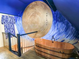 A bathroom with a wooden bath tub and wall art at The Sunday School Room in Sherborne