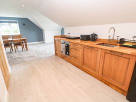 A kitchen with wooden cabinets and dining area at 6 Coswinsawsin Lane near Camborne