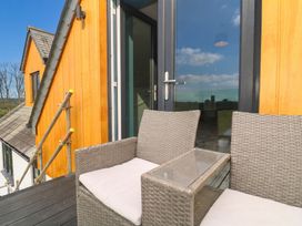 A balcony with chairs and a glass table at 6 Coswinsawsin Lane near Camborne