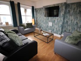 A living room with a sofa, coffee table, and television at Cornerhouse Apartment 1 in Llandudno