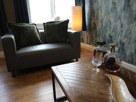 A living room with a sofa, table, and decorative items at Cornerhouse Apartment 1 Llandudno