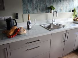 A kitchen with a sink, countertop, kettle, and food items at Cornerhouse Apartment 1, Llandudno