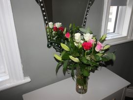 A bouquet of flowers on a table with a mirror in a living room at Cornerhouse Apartment 1 Llandudno