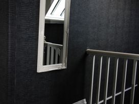 A staircase with a mirror and handrail at Cornerhouse Apartment 1 in Llandudno