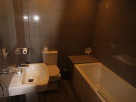 A bathroom with a sink, toilet, bathtub and mirror at Cornerhouse Apartment 1 in Llandudno
