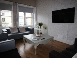 A living room with sofas, a coffee table, and a television at Cornerhouse Apartment 3, Llandudno