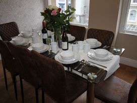A dining table set with plates, cutlery, and a flower arrangement at Cornerhouse Apartment 3 in Llandudno