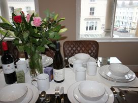 A dining table set with dinnerware and wine bottles at Cornerhouse Apartment 3 in Llandudno