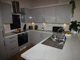 A kitchen with cabinets, oven, sink, and microwave at Cornerhouse Apartment 3 Llandudno