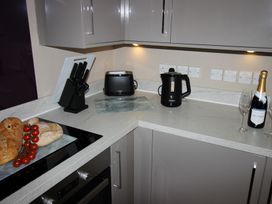 A kitchen with a kettle, toaster, and various items on the countertop at Cornerhouse Apartment 3 in Llandudno