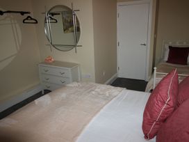 A bedroom with a bed, dressing table, and mirror at Cornerhouse Apartment 3 Llandudno