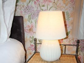 A bedside table with a lamp next to a bed at Cornerhouse Apartment 3 in Llandudno