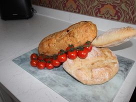 Breads and tomatoes on a cutting board at Cornerhouse Apartment 5 in Llandudno