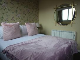 A bedroom with a bed, pillows, lamp, and mirror at Cornerhouse Apartment 5 in Llandudno