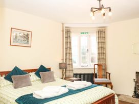 A bedroom with a bed and chair at The Cheese House near Charmouth