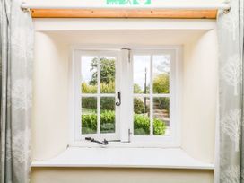 A window with curtains overlooking greenery at The Cheese House near Charmouth
