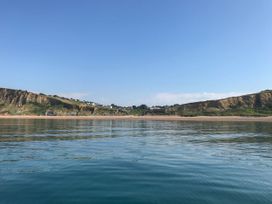 A view of cliffs and beach with water in the foreground at The Cheese House near Charmouth