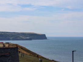 A view of the sea and cliffs with people walking at 26 Metropole Towers in Whitby