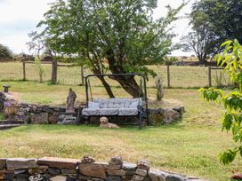 A garden with a swing seat and a dog at Little Moorgate in Okehampton