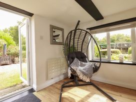 A room with a hanging chair and window at Honey Bee Cottage in Menheniot