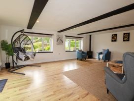 A living room with a hanging chair and seating area at Honey Bee Cottage in Menheniot