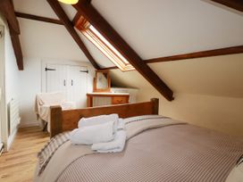 A bedroom with a bed and window at Honey Bee Cottage Menheniot