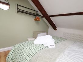 A bedroom with a bed and hangers at Honey Bee Cottage Menheniot