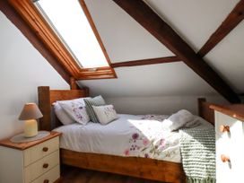 A bedroom with a bed and a lamp at Honey Bee Cottage in Menheniot