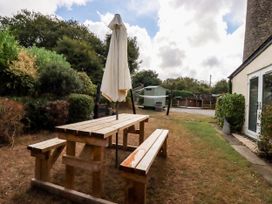 A garden with a table and benches under an umbrella at Honey Bee Cottage in Menheniot