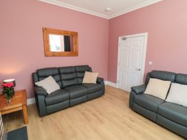 A living room with sofas, a mirror, and a door at Portobell House in Bridlington