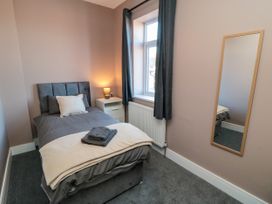 A bedroom with a bed and a mirror at Portobell House in Bridlington