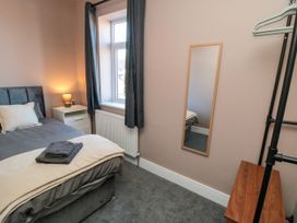 A bedroom with a bed, nightstand, lamp and mirror at Portobell House in Bridlington