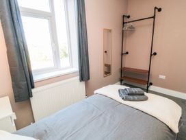 A bedroom with a bed, shelf, mirror, and window at Portobell House in Bridlington