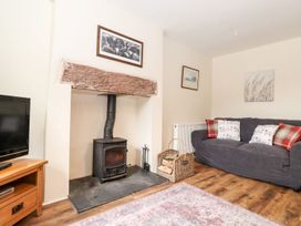 A living room with a wood stove and television at Irt Cottage in Seascale