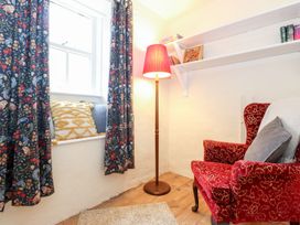 A snug with a red armchair and decorative curtains at Irt Cottage Seascale