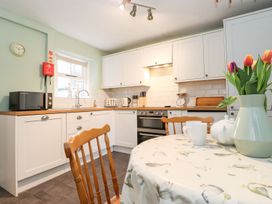A kitchen with a table and chairs and a microwave at Irt Cottage in Seascale