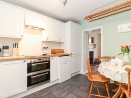 A kitchen with cabinets, stove, and dining table at Irt Cottage in Seascale