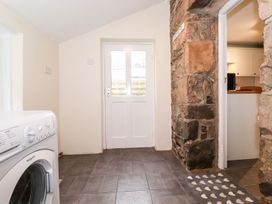 A laundry room with a washing machine and stone wall at Irt Cottage Seascale