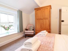 A bedroom with a bed, wardrobe, chair and window at Irt Cottage in Seascale