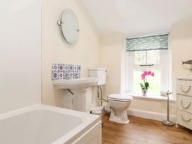 A bathroom with a bathtub, toilet, sink, and window at Irt Cottage Seascale