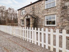 A stone building with a white fence and gravel path at Irt Cottage in Seascale