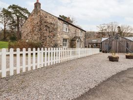 A stone house with a white fence and gravel driveway at Irt Cottage in Seascale