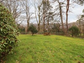 A garden with a table and chairs surrounded by trees at Irt Cottage Seascale