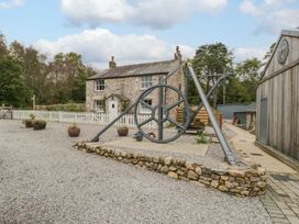 An outdoor area with a stone house and mechanical wheel at Irt Cottage in Seascale
