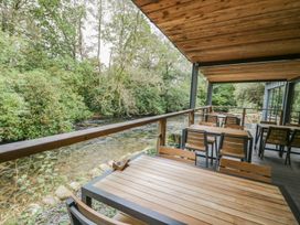 An outdoor seating area with tables and chairs overlooking a river at Irt Cottage in Seascale